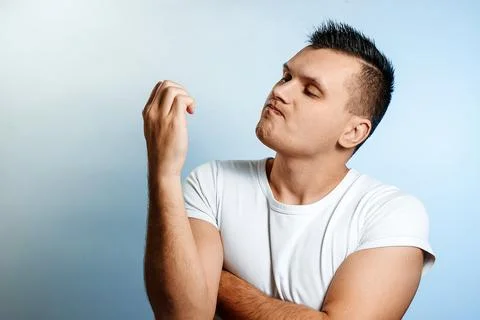 Portrait of a white man on a light background, looking at his nails. The conc Stock Photos