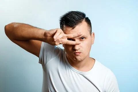 Portrait of a white man on a light background, gesture two fingers near the e Stock Photos