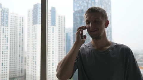 Portrait of a white man making a call standing by the window. Video stock 157056362