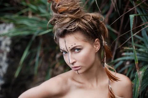 Portrait of wild amazon girl with art makeup and feathers in her hair Stock Photos