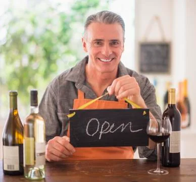 Portrait of wine store owner holding open sign Stock Photos
