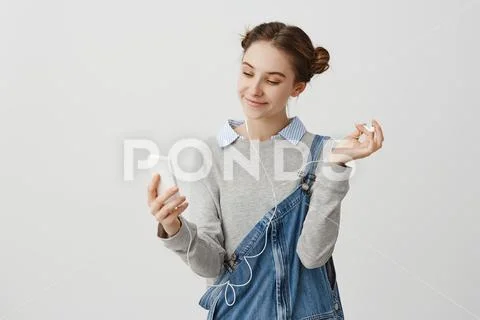 Portrait of woman 20s looking on screen of cellphone with pleasant wide smile Stock Photos