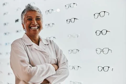 Portrait, woman and smile of optician with arms crossed in shop or store for Stock Photos