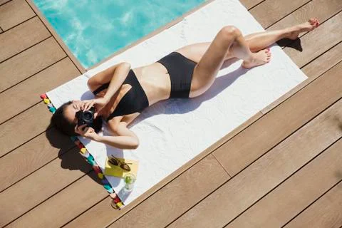Portrait woman in bikini sunbathing, using digital camera at poolside Stock Photos