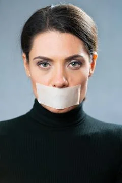 Portrait of a woman with closed mouth a white tape. censorship concept. restrain Stock Photos