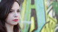 portrait of woman is crying leaning against a wall painted with murals HD Footage