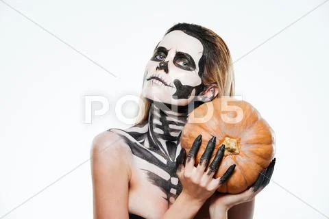 Portrait of woman with halloween skeleton makeup holding pumpkin Stock Photos