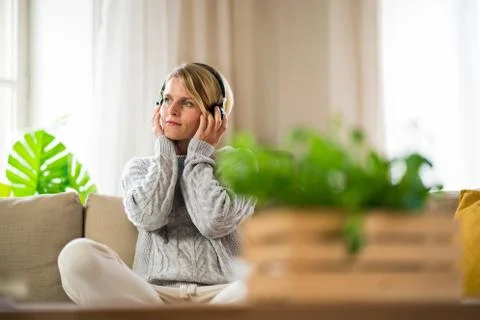 Portrait of woman with headphones relaxing indoors at home, mental health care Stock Photos