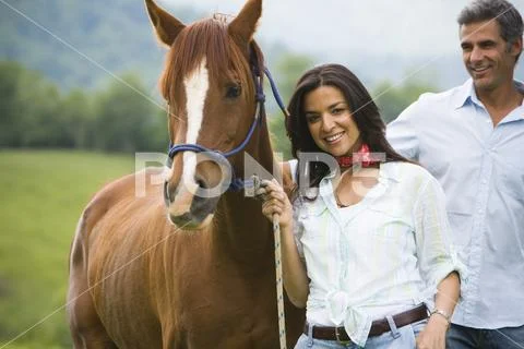 Portrait of a woman holding the reins of a horse with a man beside her Stock Photos