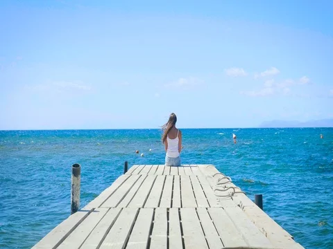 Portrait of a woman sitting on a wooden pier, looking at the sea feels free, a b Stock Footage