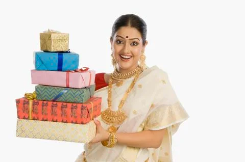 Portrait of a woman in traditional saree holding gifts and smiling Stock Photos