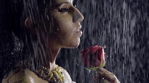 The portrait of a woman, on whom water drips, she brings a red rose to her neck Stock Footage