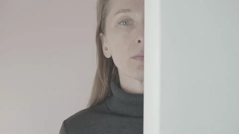 Portrait of a woman whose face is half behind a white wall and then completely h Stock Footage 233001393