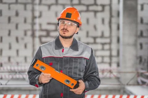 Portrait of a working foreman in a helmet with a level tool in his hands during Stock Photos