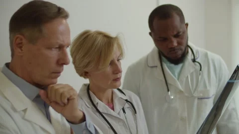 Portrait of worried puzzled multicultural physicians examining mri scan at Stock Footage 164532539