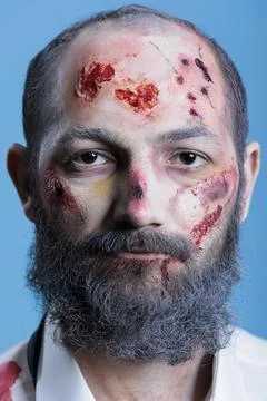 Portrait of wounded actor dressed as horror movie zombie, studio background Stock Photos