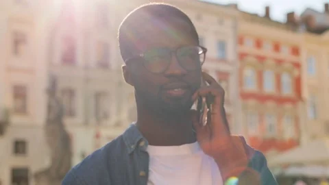 Portrait of young african man in blue shirt talking on mobile phone with friend Stock Footage