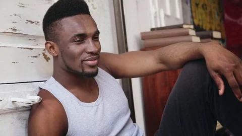 Portrait of young african man posing to camera. Handsome male in pajamas sitting Stock Footage
