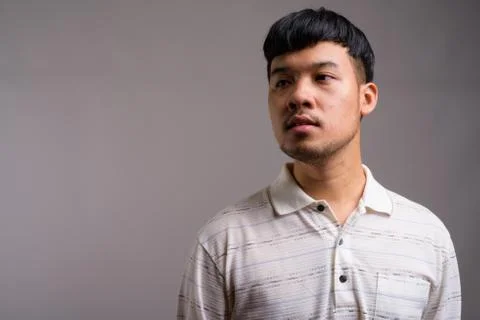 Portrait of young Asian man against gray background Stock Photos