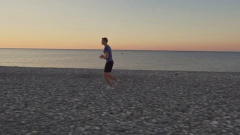 Portrait of a young athletic man doing a jog on the background of the sea at Vídeo Stock 118246560