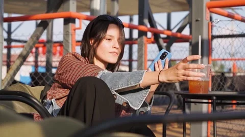 Portrait of a young attractive brunette looking into a smartphone while sitting Stock Footage 246797384