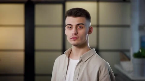 Portrait of a young attractive guy who looks into the camera with a serious face Stock Footage 236399092