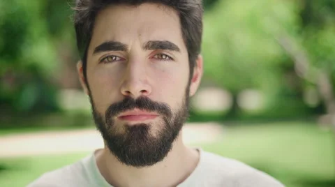 Portrait young attractive man looking serious at the camera in the park Stock Footage 64773280