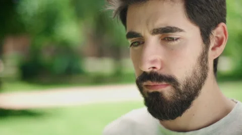 Portrait young attractive man looking serious at the camera in the park Stock Footage 64773701