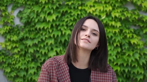 Portrait Young attractive smiling smiling brunette girl. Green plant background Stock Footage 246797356