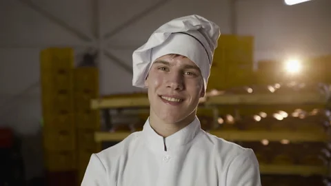 Portrait of young baker in uniform looking with smile at camera in a bakery Vídeo Stock 147259559