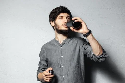 Portrait of young bearded guy, drinking water from black stainless bottle. Stock Photos