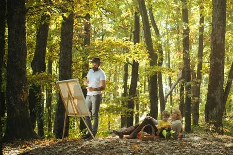 Portrait of young bearded man in hat painting a picture using brushes and modern Stock Photos
