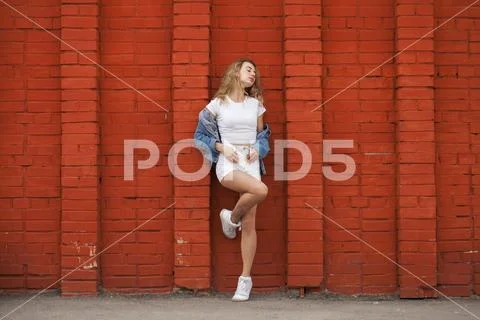 Portrait of a young beautiful blonde girl in white shorts and a vest posing a Stock Photos