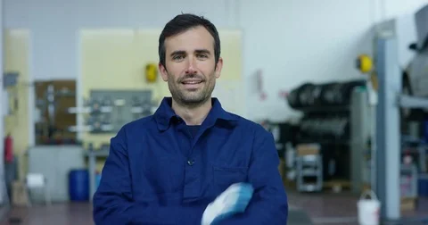 Portrait of a young beautiful car mechanic in a car workshop, in the background Stock Footage