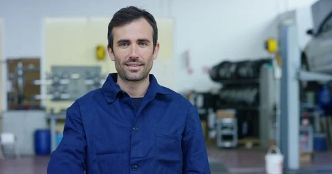 Portrait of a young beautiful car mechanic in a car workshop, in the background Stock Footage
