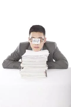 Portrait of young bisinessman leaning on stack of files Foto stock