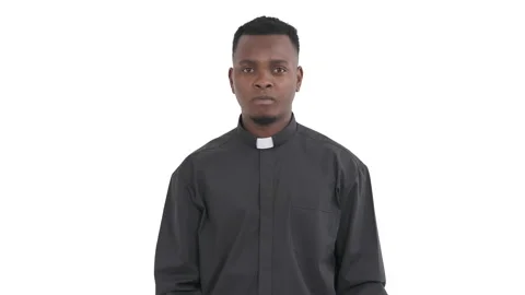 Portrait of young black priest looking at camera, pointing to himself as if Stock Footage 134865026