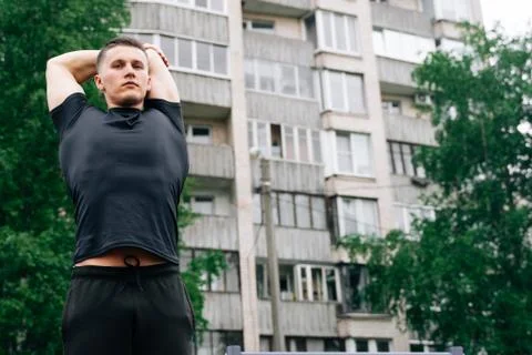 Portrait of young bodybuilder stretching back muscles. Against the background Stock Photos