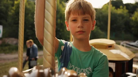 Portrait young boy on carousel look at camera sunset sunlight happy child Stock Footage 100581647