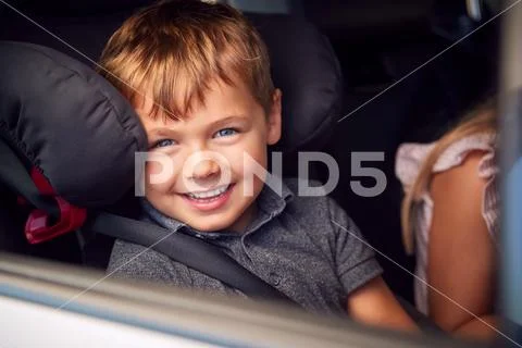 Portrait Of Young Boy Sitting In Child Safety Seat On Car Journey Looking Out Of Stock Photos