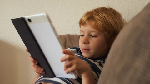 Portrait of young boy while surfing the internet on tablet. 스톡 동영상 121728748