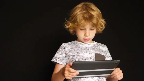 Portrait of young boy while surfing the internet on tablet. 库存影片 151236112