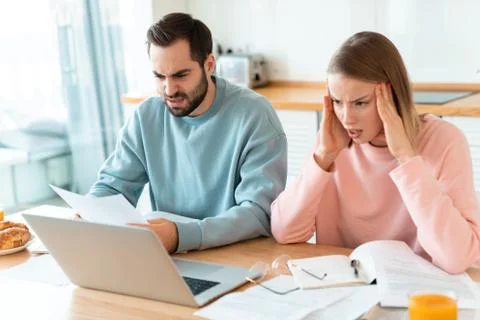 Portrait of young brooding couple working with laptop and documents Stock Photos