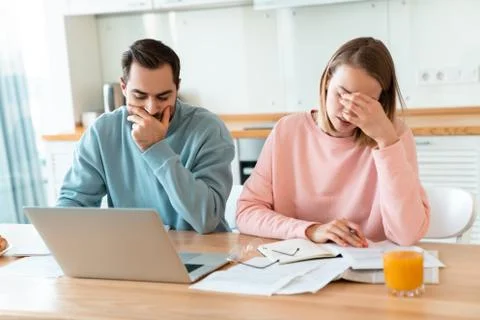 Portrait of young brooding couple working with laptop and documents Stock Photos