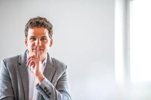 Portrait of young businessman with finger on lips in office Stock Photos