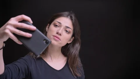 Portrait of young caucasian long-haired brunette girl making selfie-photos using Video stock 101568969