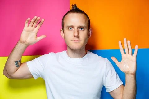 Portrait of a young, cheerful guy on a multi-colored background, dressed in a Stock-Fotos