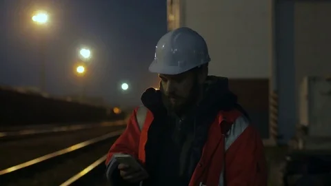 Portrait of young construction worker in helmet using phone at night. 4k Video stock 83760766