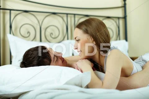 Portrait of young couple lying in bed and looking at one another Stock Photos