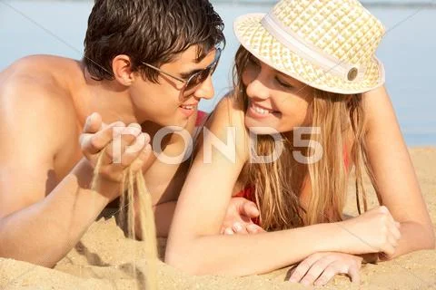Portrait of a young couple lying on sand and looking at each other Stock Photos